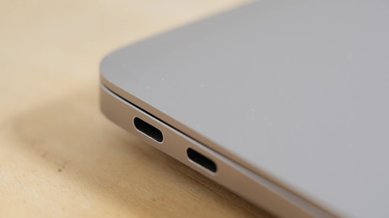 Tanka bočna strana srebrnog laptopa sa USB-C portovima na drvenom stolu